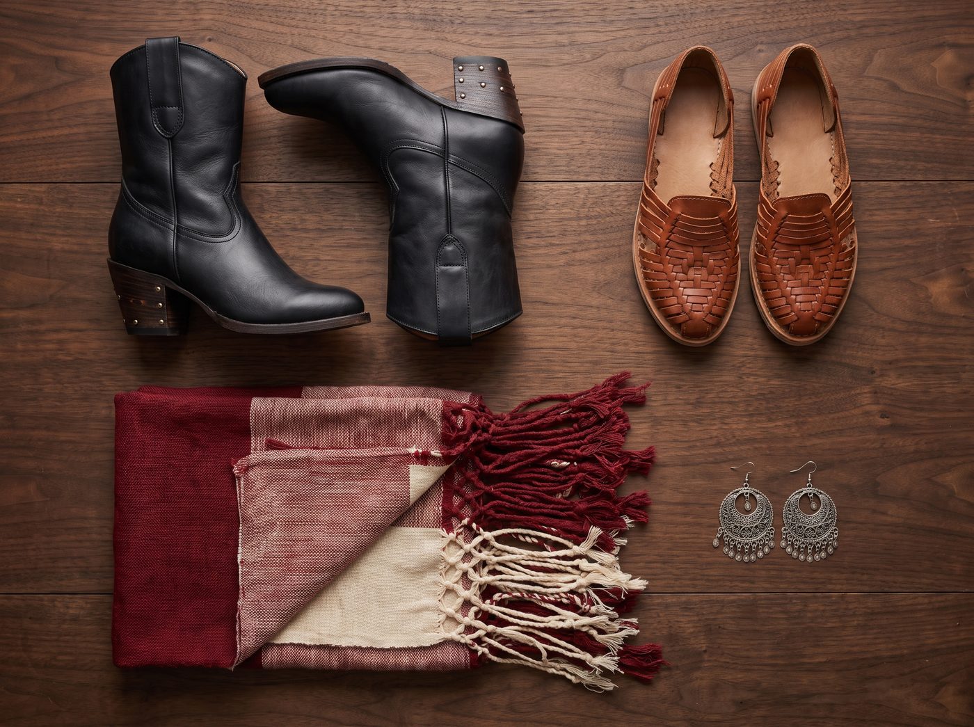Flat lay of folklorico dance boots, leather huaraches, a fringed rebozo and silver filigree earrings